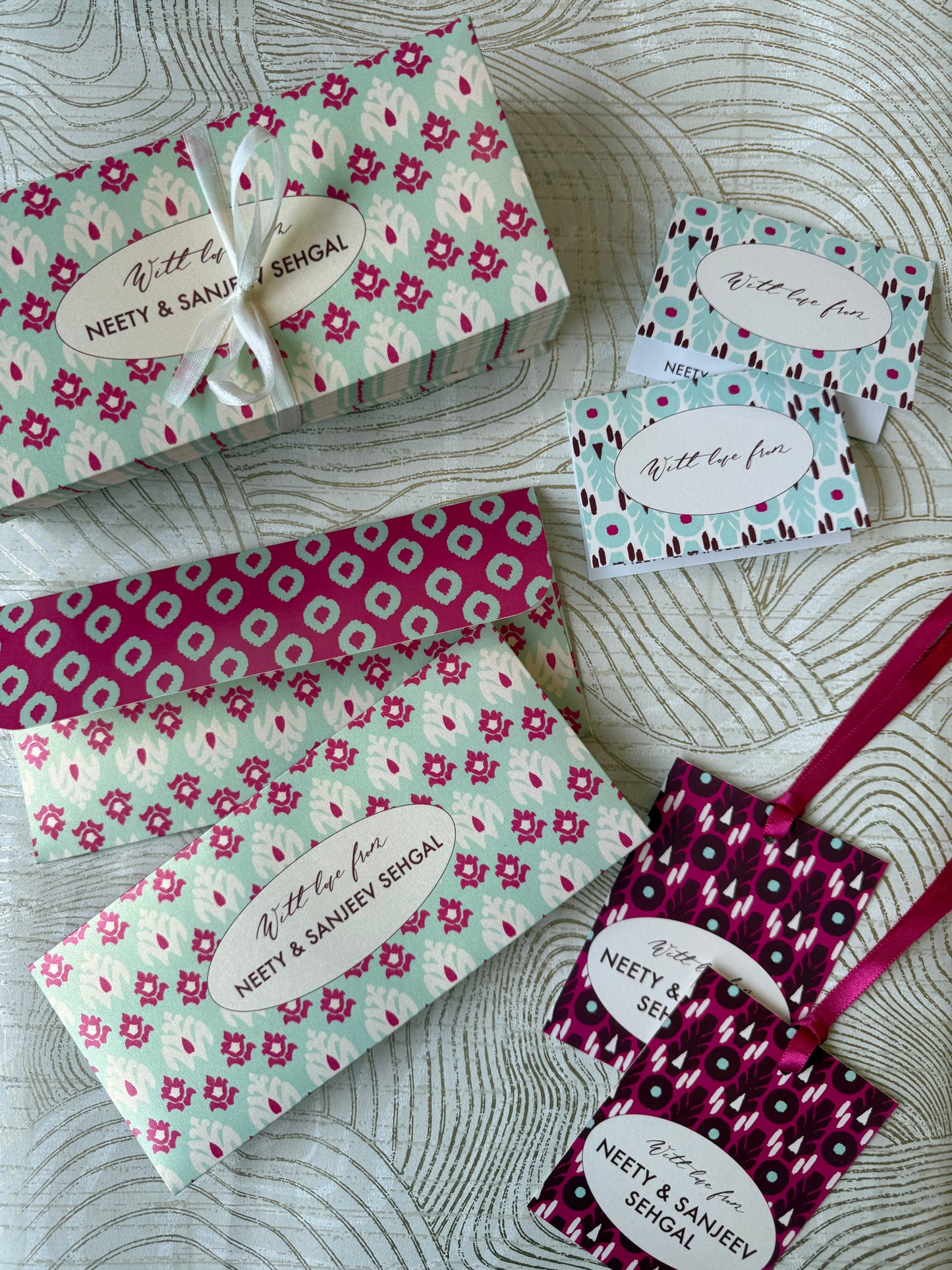 Money envelopes and gift tags with ikat floral patterns and ribbons on a textured surface
