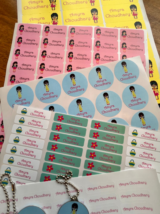 Several printed sticker sheets laid out on a wooden surface, featuring repeated cartoon character illustrations different color schemes including yellow, pink, light blue, and green.