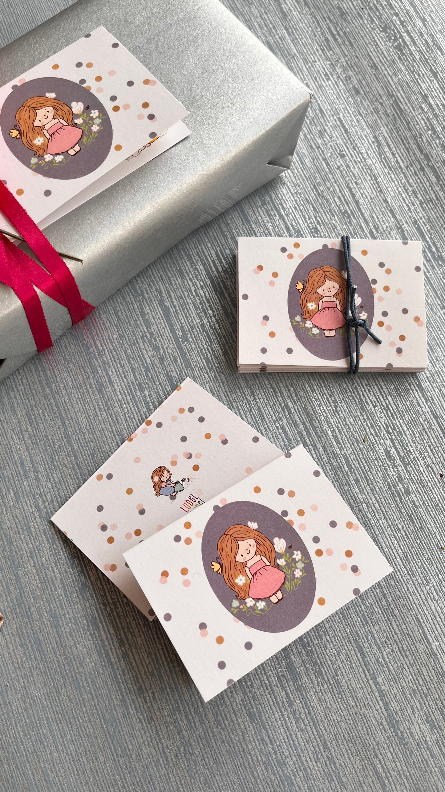 Folded gift card personalised with a name featuring a cute girl on an oval grey background surrounded by polka dots