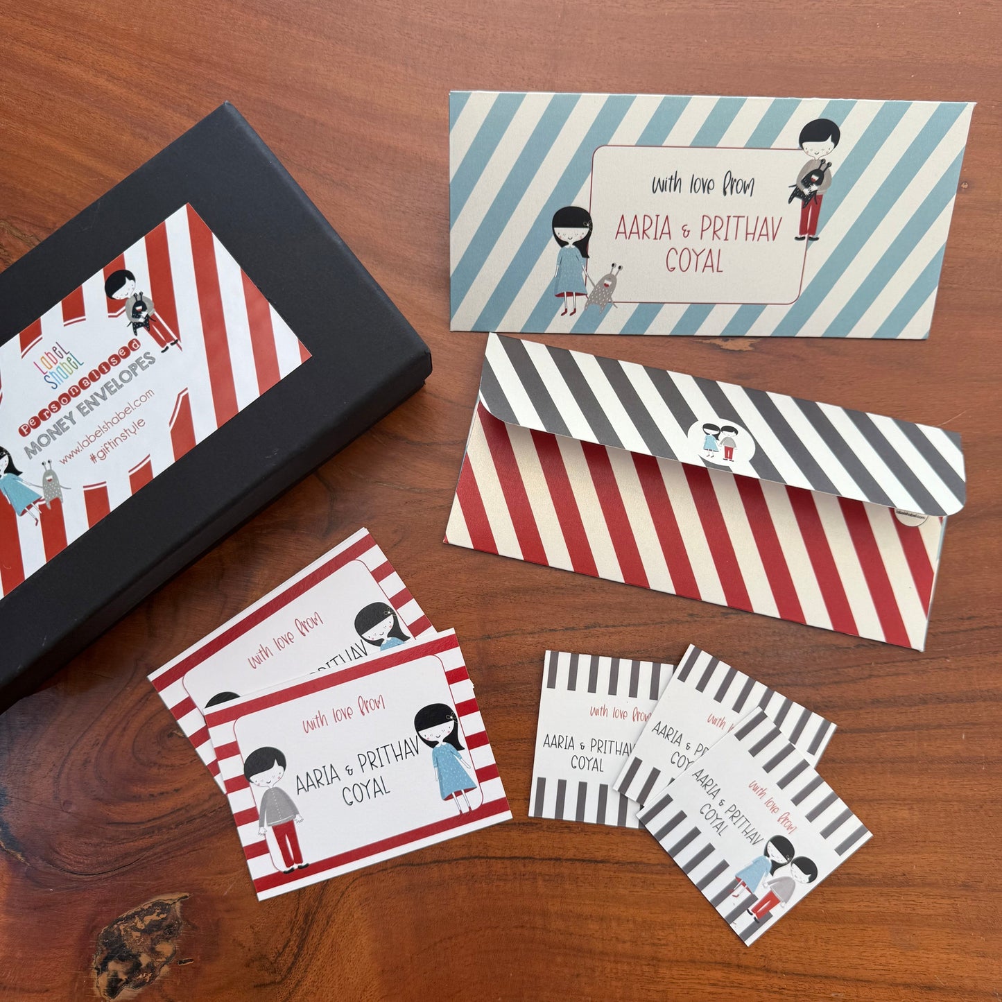 Set of personalized envelopes and cards with striped designs on a wooden surface
