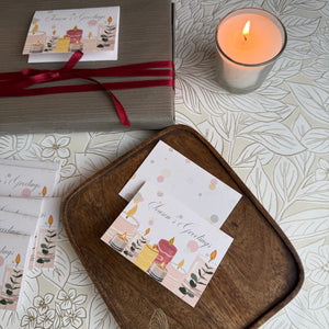 Greeting cards with candles and gift box on a decorative surface