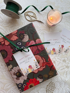 Floral notebook with a decorative tag on a textured surface with a candle and ribbon.