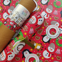 A roll of personalized wrapping paper with Christmas-themed designs, placed next to a set of printed labels with 'Snowman' and other Christmas-related words.
