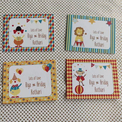 Four personalized circus-themed greeting cards arranged in a 2x2 grid on a beige polka dot background. The cards feature colorful borders and cartoon illustrations of clowns, lions, and balloons, with the text 'Lots of Love Riya & Hriday Kothari'.