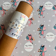 A roll of personalized wrapping paper with a dancing unicorn motif, placed on a background with various designs including snowflakes and cute creatures.