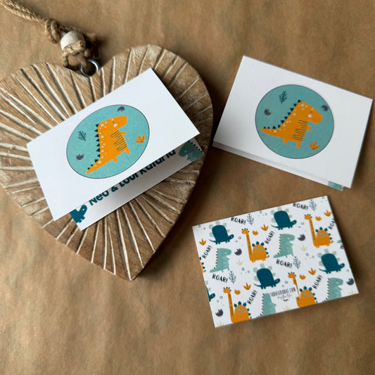 A set of children's birthday cards featuring cute dinosaur illustrations, styled on a brown kraft paper background with a wooden heart-shaped box.