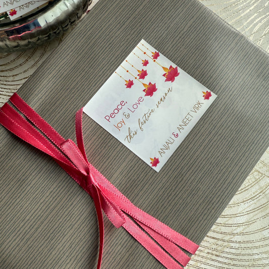 Gift wrapped in brown paper with a pink ribbon and a decorative tag on a textured surface.