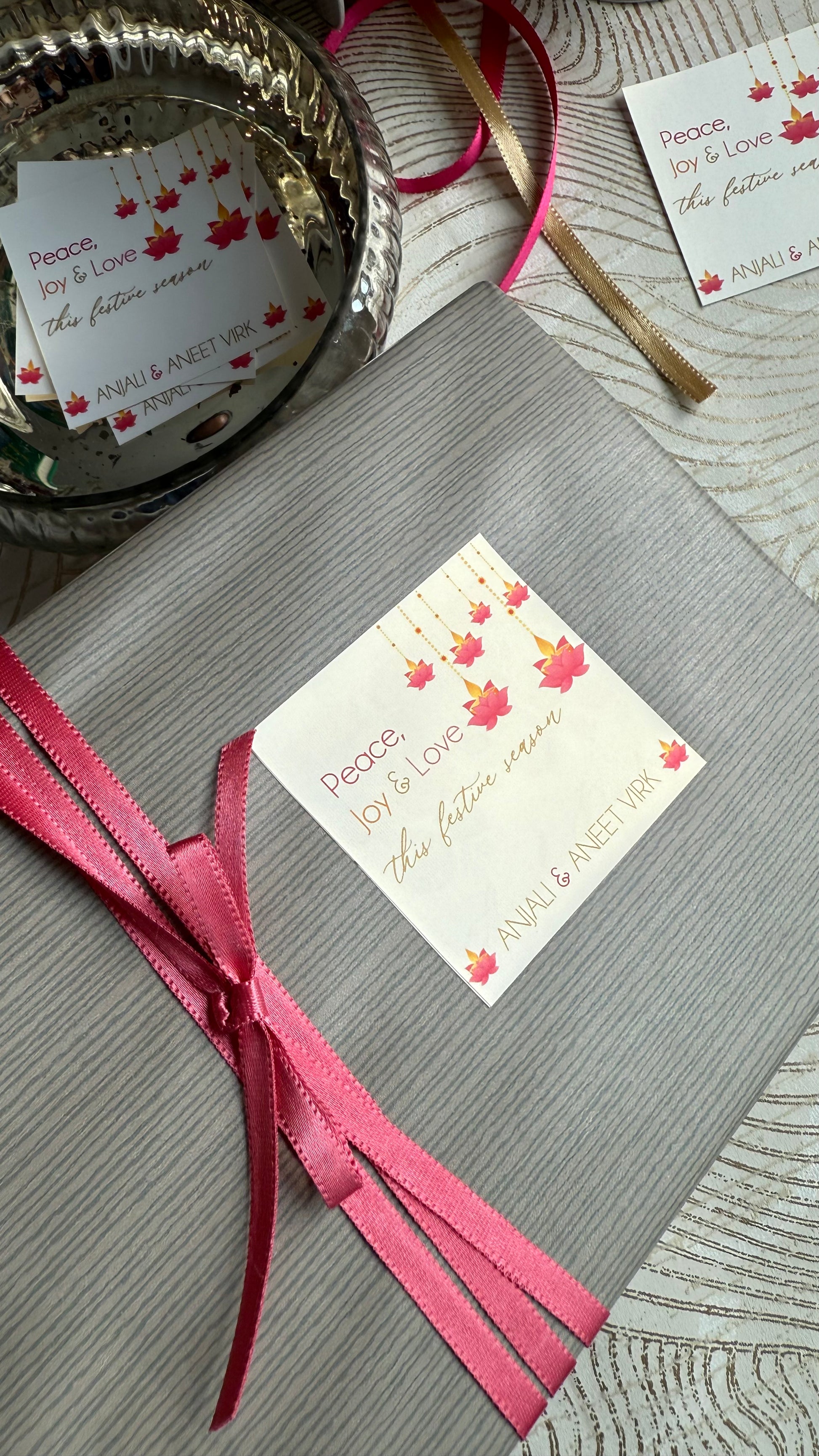 Gray gift box with pink ribbon and decorative card on a textured surface