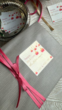 Gray gift box with pink ribbon and decorative card on a textured surface