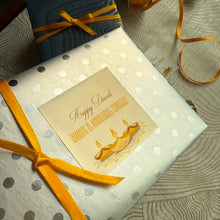 Gift box with a 'Happy Diwali' card and decorative ribbon on a textured surface.