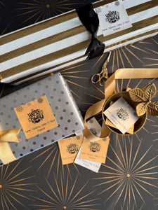 Gift box with gold ribbon and decorative tags on a patterned surface