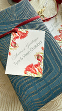 Floral gift tag on a blue textured surface with a red ribbon