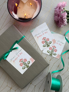 Gift box with floral card, candle, and ribbons on a textured surface