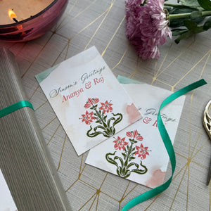 Two greeting cards with floral designs on a decorative surface with a candle and flowers.