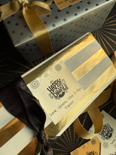 Gift box with gold ribbon and decorative label on a patterned background