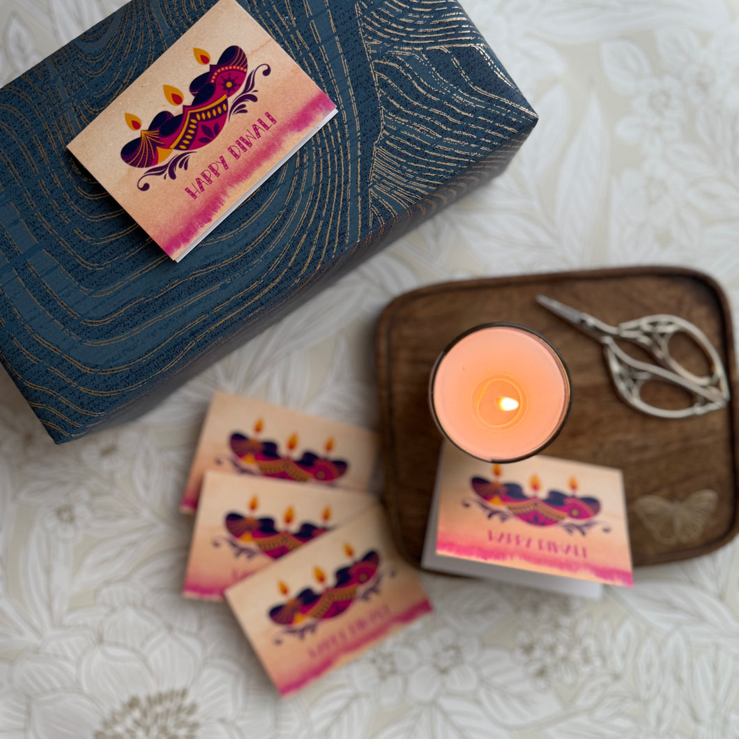 Candle with decorative packaging and a pair of scissors on a textured surface