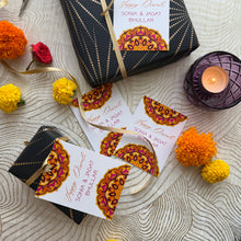 Decorative gift boxes with personalized labels on a textured surface with flowers and a candle.
