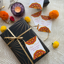 Decorative gift box with a ribbon, candles, and floral elements on a textured surface.
