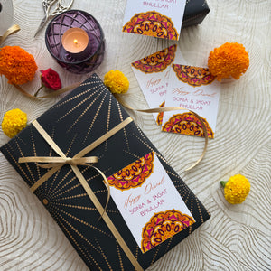 Decorative gift box with a ribbon, candles, and floral elements on a textured surface.