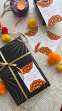 Gift box with decorative label on a textured surface with marigold flowers and candles.