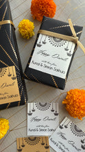 Decorative Diwali gift boxes with personalized labels on a patterned surface.