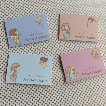 Four small rectangular cards arranged on a beige surface with a brown polka-dot pattern. Each card has a pastel background in blue, pink, or light blue, with a cute illustration of a girl and the text 'with love Annayat Uppal'.