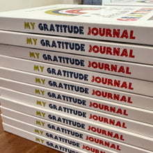Stack of 'My Gratitude Journal' books on a wooden surface