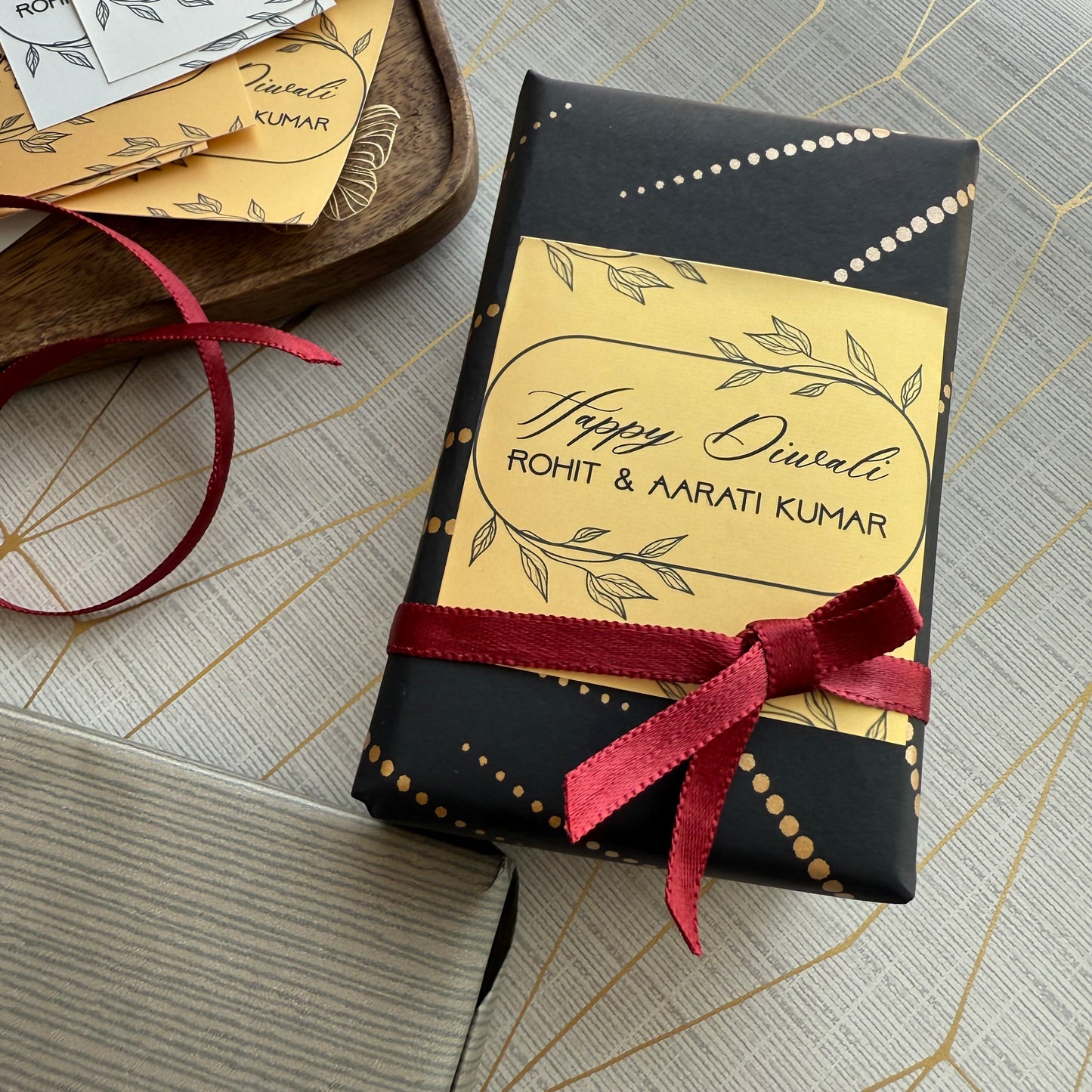 Gift box with personalized 'Happy Diwali' label and red ribbon on a textured surface.