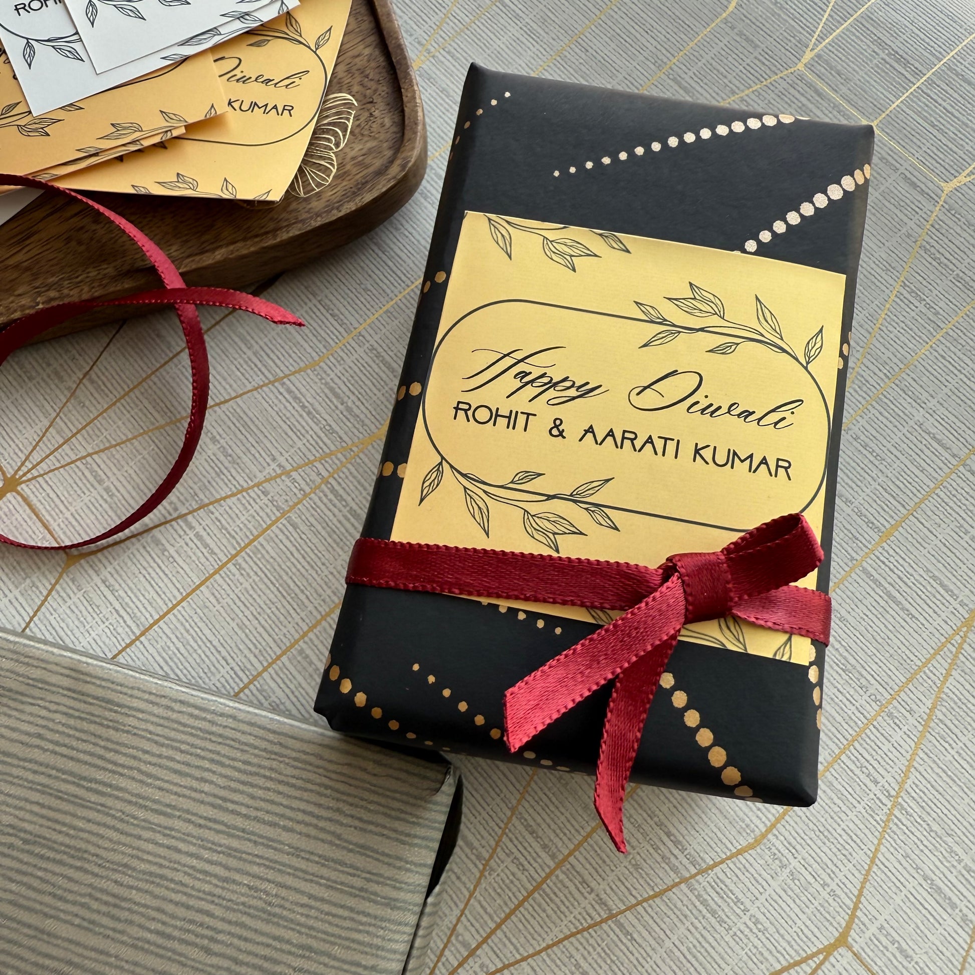 Gift box with personalized 'Happy Diwali' label and red ribbon on a textured surface.