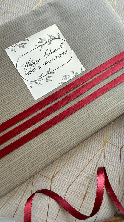Gift box with a red ribbon and a diwali labelon a textured surface