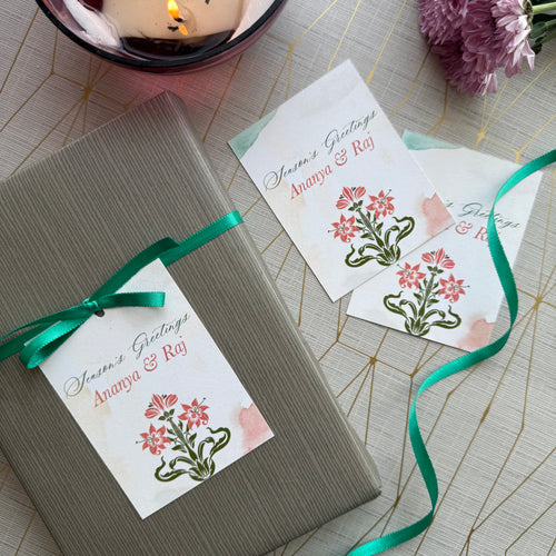Gift box with floral card and green ribbon on a patterned surface