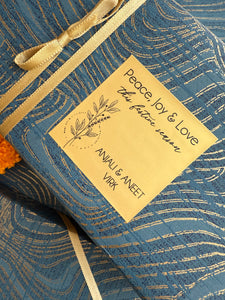 Blue gift box with gold ribbon and a decorative label on a matching blue background