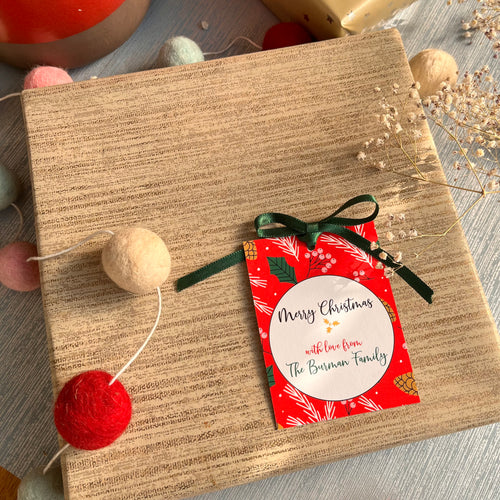 Bright red Background with xmas elementss of pine cone, holly leaf berries with a green bow decorating a xmas gift