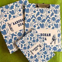 A set of school supplies with a blue and white design, including a notebook, clipboard, and a ring folder, all personalized with 'Aarohan DuA' written on the covers.