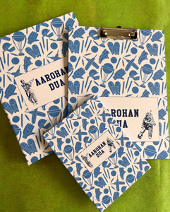 A set of school supplies with a blue and white design, including a notebook, clipboard, and a ring folder, all personalized with 'Aarohan DuA' written on the covers.