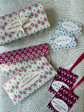Money envelopes and gift tags with ikat floral patterns and ribbons on a textured surface
