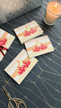 Set of greeting cards with floral design on a textured surface with a candle and scissors.