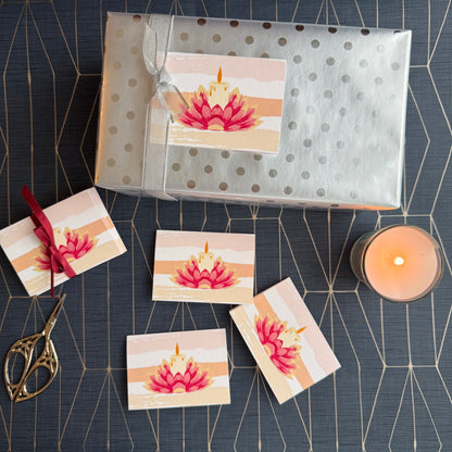 Packaged gift with matching cards on a decorative surface with a candle.