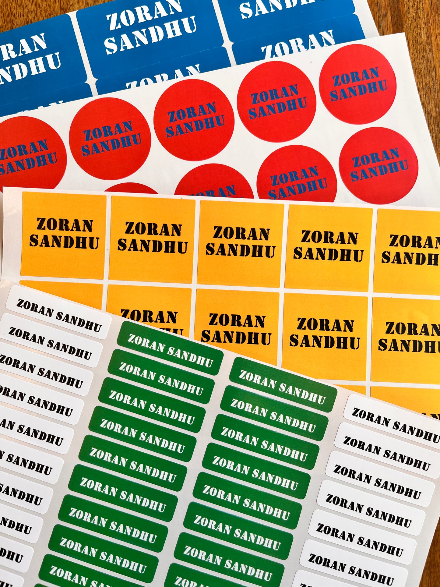 waterproof school name labels personalised with a aname in bold colours white, red, yellow, and green backgrounds