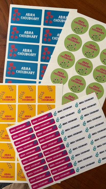 Several sheets of personalised waterproof tsickers ncluding blue rectangular labels, green round labels, yellow rectangular labels, and pink rectangular labels, all printed with the name Abia Choudhary and small flowers