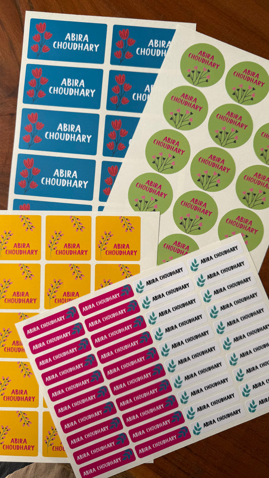 Several sheets of personalised waterproof tsickers ncluding blue rectangular labels, green round labels, yellow rectangular labels, and pink rectangular labels, all printed with the name Abia Choudhary and small flowers