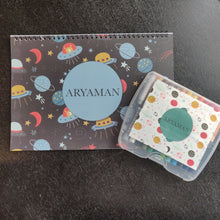 a drawing set of art book and box of personalised crayons with a space themed design rockets spaceships planets stars
