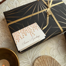 Gift box with gold ribbon and 'Season's Greetings' card on a decorative surface