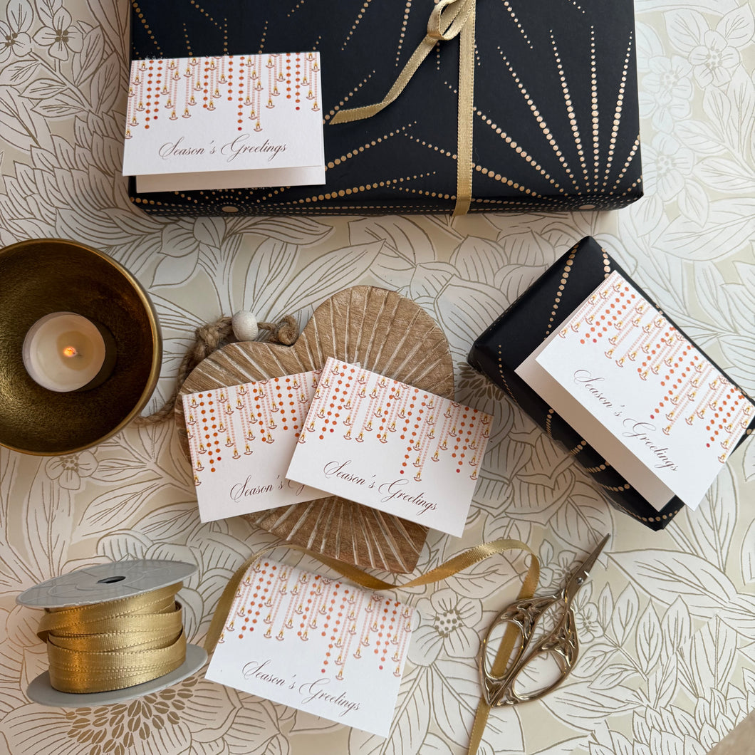 Gift-wrapped items with 'Season's Greetings' cards on a decorative surface.