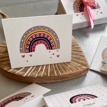 Folded gift tag personalised with a name featuring a colourful cute rainbow and hearts on a white background