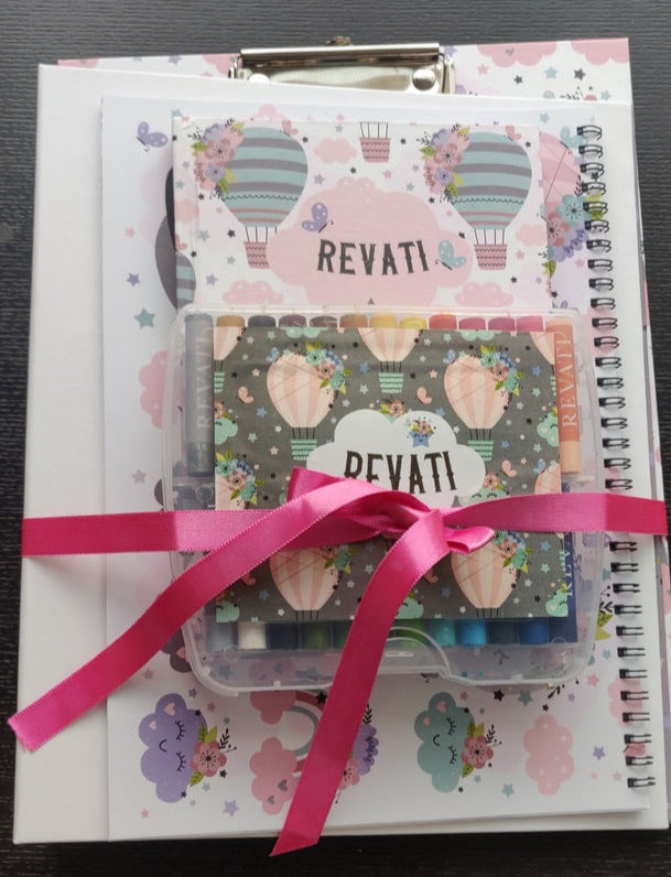 A set of clipboard, personalised crayons and note book tied together with in a pink ribbon