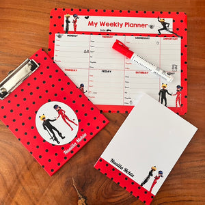 Weekly planner, note page and clipboard with red and black polka dot design on a wooden surface