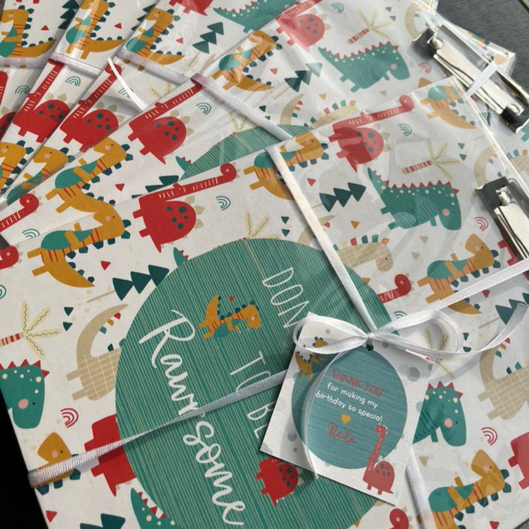 clipboards wrapped with a card and ribbon in dinosaur theme as return gifts for birthdays