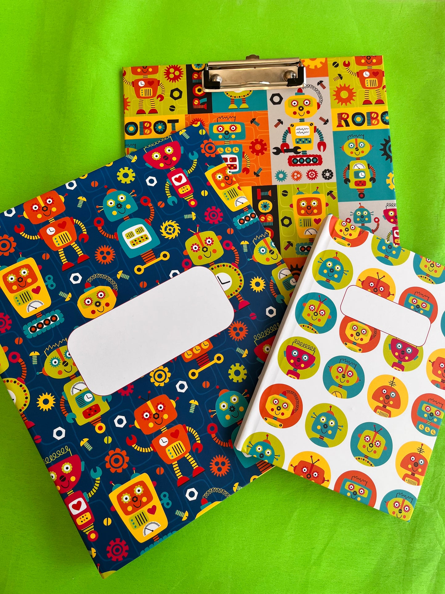 Colorful robot-patterned set of file folder, clipboard and note book on a green background