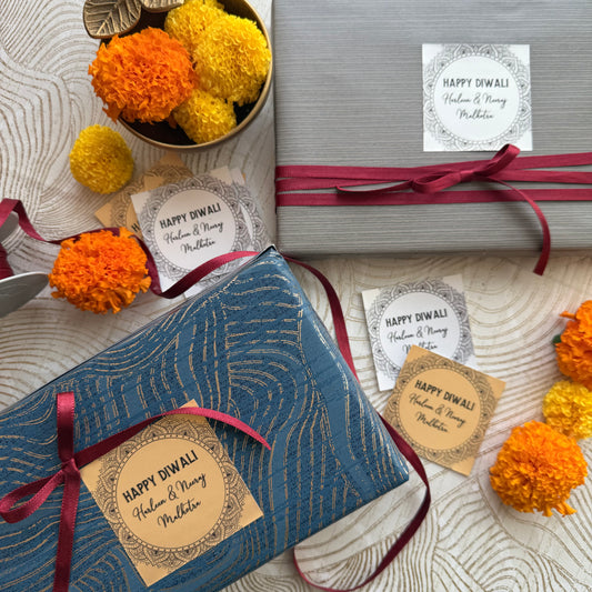 Gift boxes with 'Happy Diwali' tags and decorative marigold flowers on a textured surface.